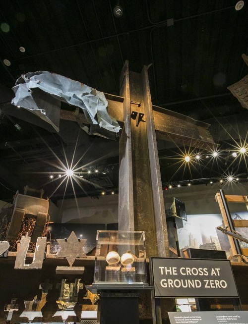 The steel World Trade Center cross is displayed at the Museum. Other artifacts surround the cross.
