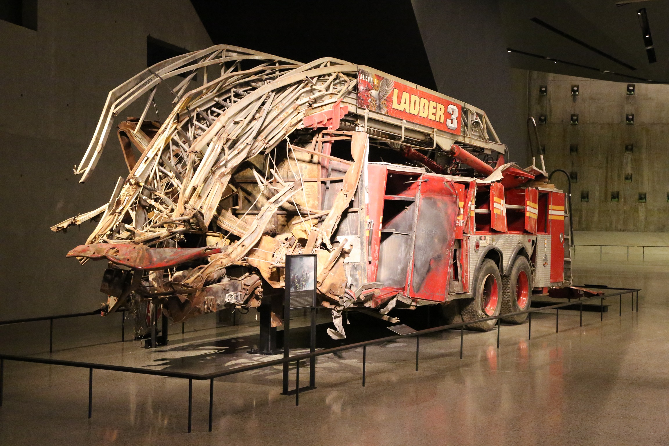 The heavily damaged truck of FDNY Ladder Company 3 stands in the Museum’s Foundation Hall. The front of the truck is completely gone and much of what remains is twisted hunks of metal.