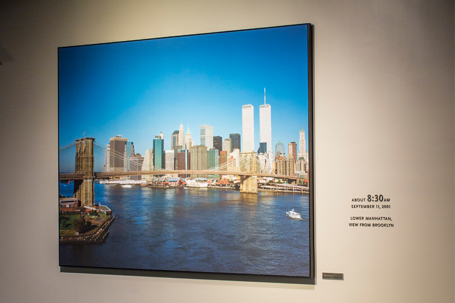 A large framed photo on a white wall shows the lower Manhattan skyline on the morning of 9/11 before the Twin Towers before the attacks.