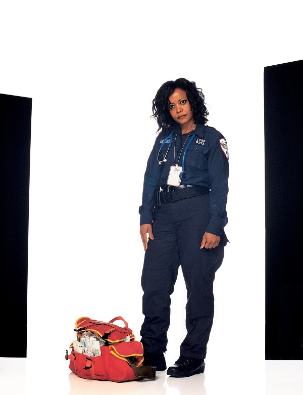 Juana Lomi wears her uniform and stands next to her bag as she poses for a photo for Joe McNally’s “Faces of Ground Zero.”