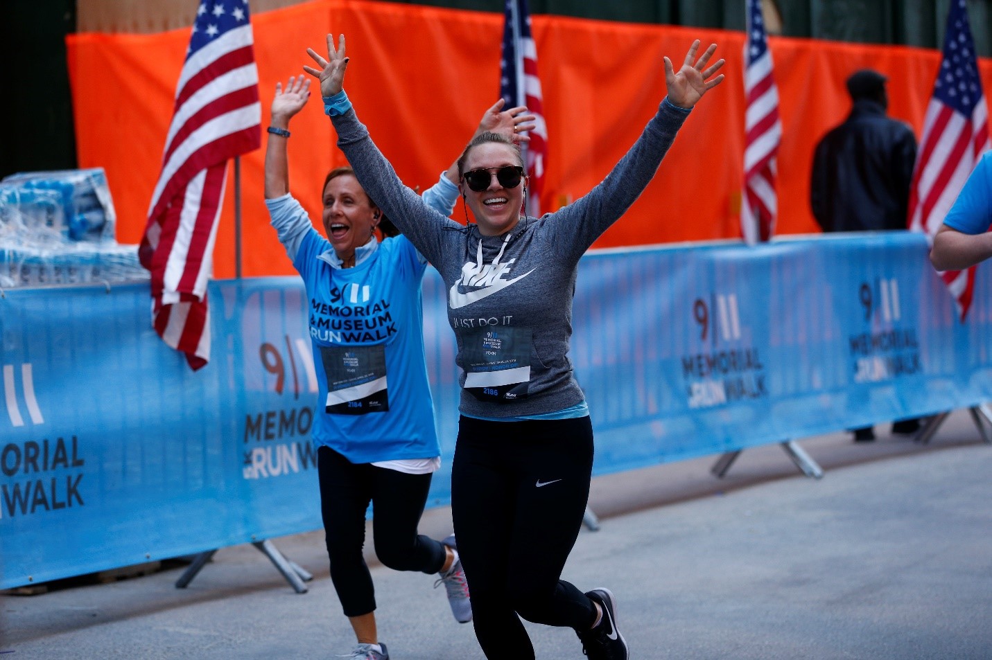 Two participants wave as they run along the route of the annual 9/11 Memorial & Museum 5K Run/Walk and Community Day.