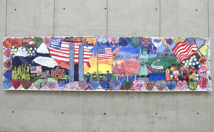 A vibrantly colored children's mural featuring patriotic imagery hangs against a stone wall in the Museum's Tribute Walk gallery.