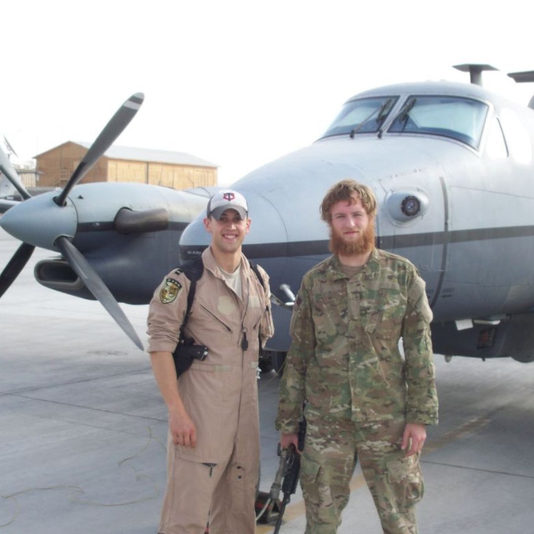 Phil Caruso (right) in uniform with fellow servicemember, in front of military plane