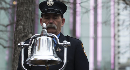 A uniformed member of the FDNY rings a silver bell to commemorate the 1993 World Trade Center bombing