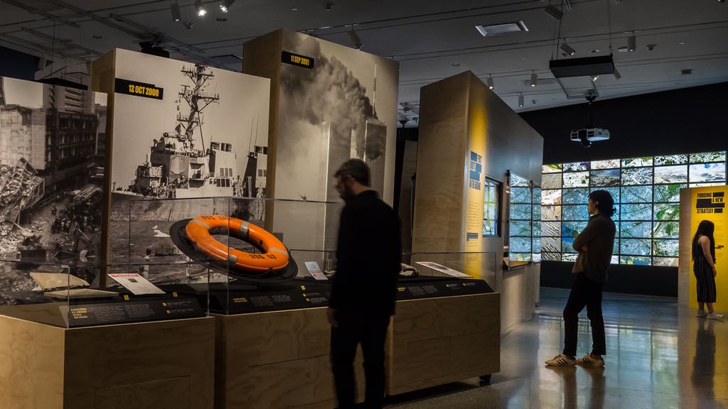 Museum visitors observe installations in a gallery space.