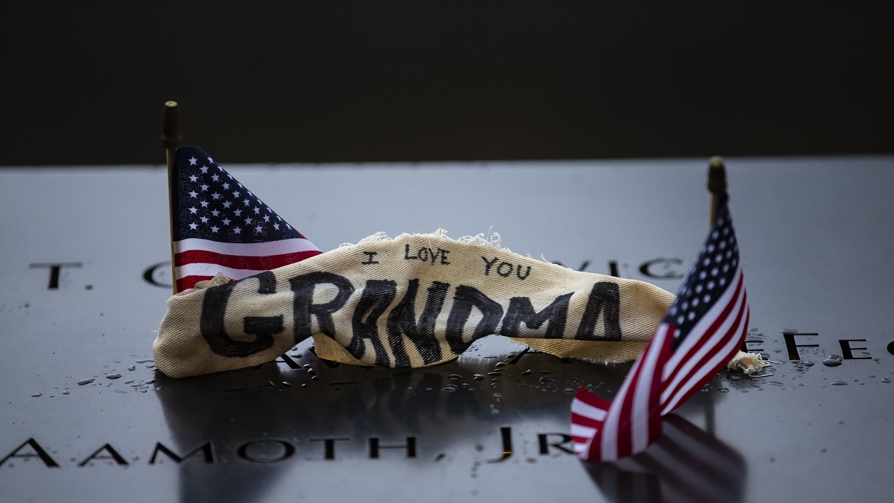 A cloth with a hand-written note has been placed at a victim’s name on a bronze parapet at the Memorial. The cloth reads “I love you grandma” and sits between two, small American flags.