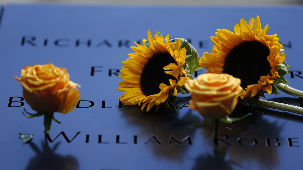 Two sunflowers and two yellow roses lie next to several names that are etched in the bronze parapets of the Memorial.