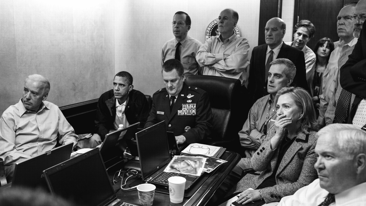 President Obama, Vice President Biden, Secretary of State Hillary Clinton, and other people sitting and standing around a conference table watching offscreen.