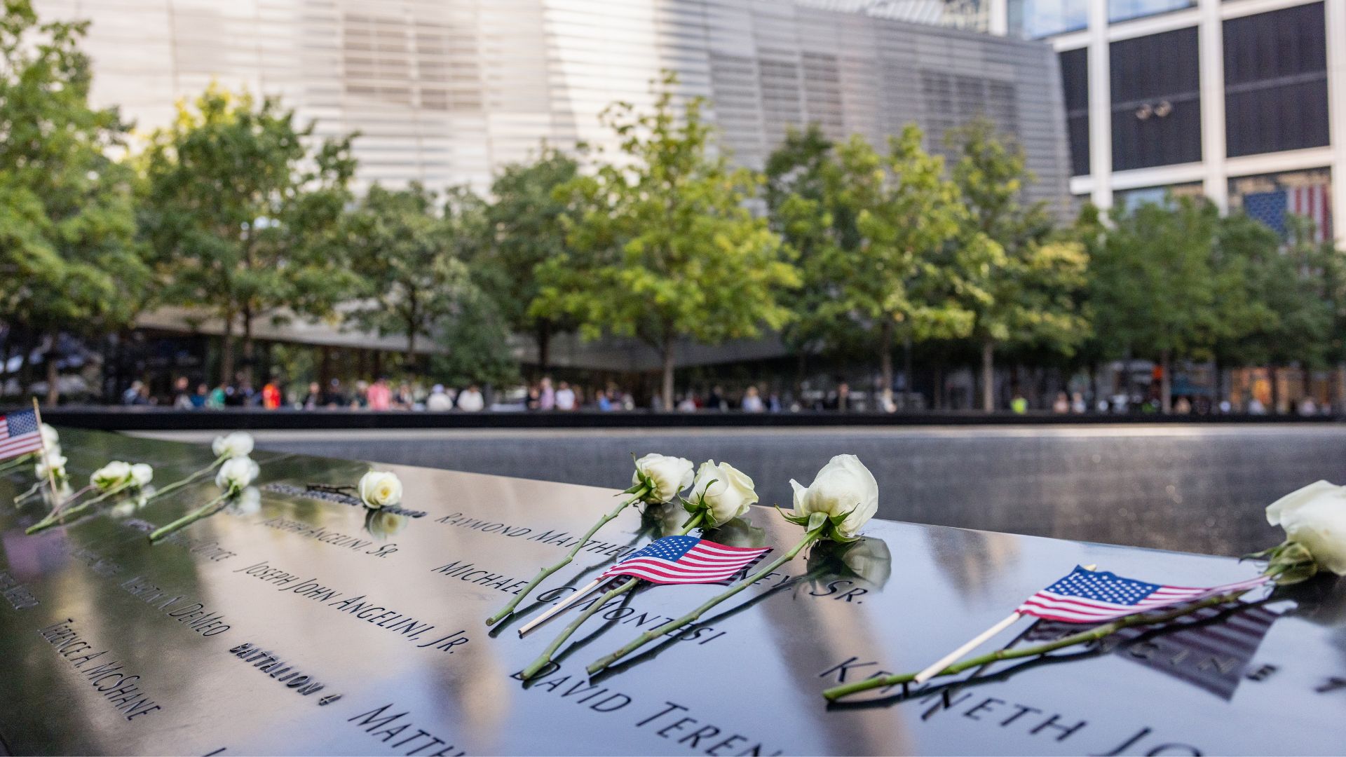 White roses and small American flags on a bronze Memorial parapet