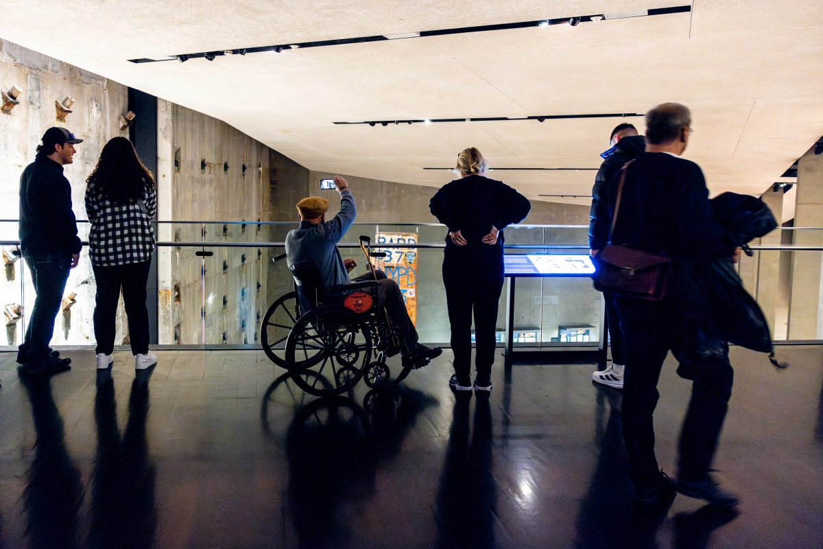 some people look over the edge of a glass wall down into the 9/11 Museum