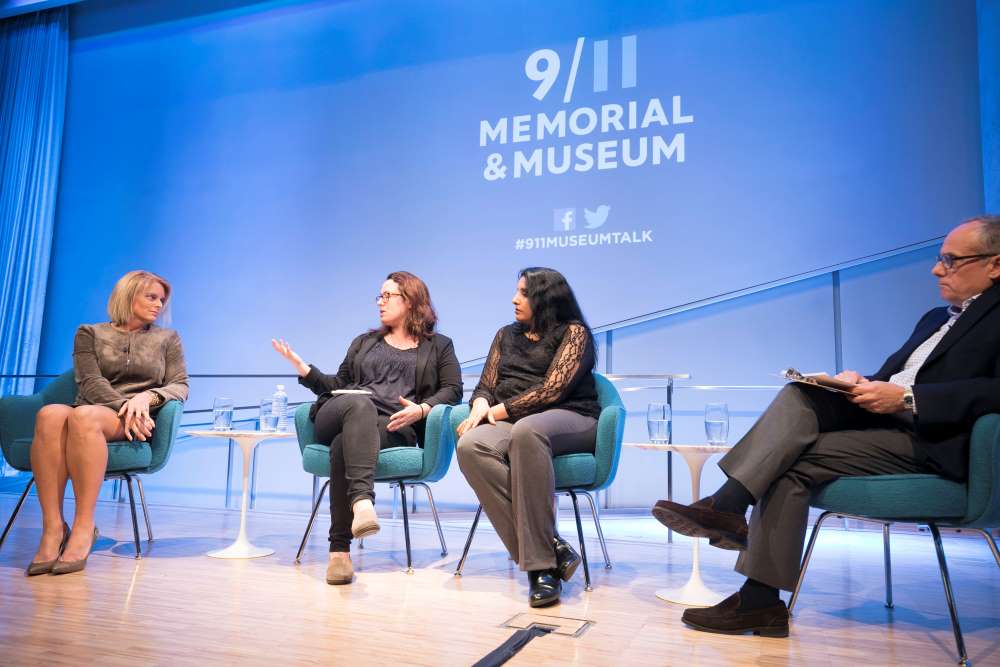 NY1 anchor Kristen Shaughnessy, New York Times correspondent and CNN analyst Maggie Haberman, and Associated Press reporter Deepti Hajela are seen seated onstage at the Museum Auditorium. Haberman is speaking as the others listen. Clifford Chanin, the executive vice president and deputy director for museum programs, listens and holds a clipboard. The 9/11 Memorial & Museum logo is projected on a wall above them.