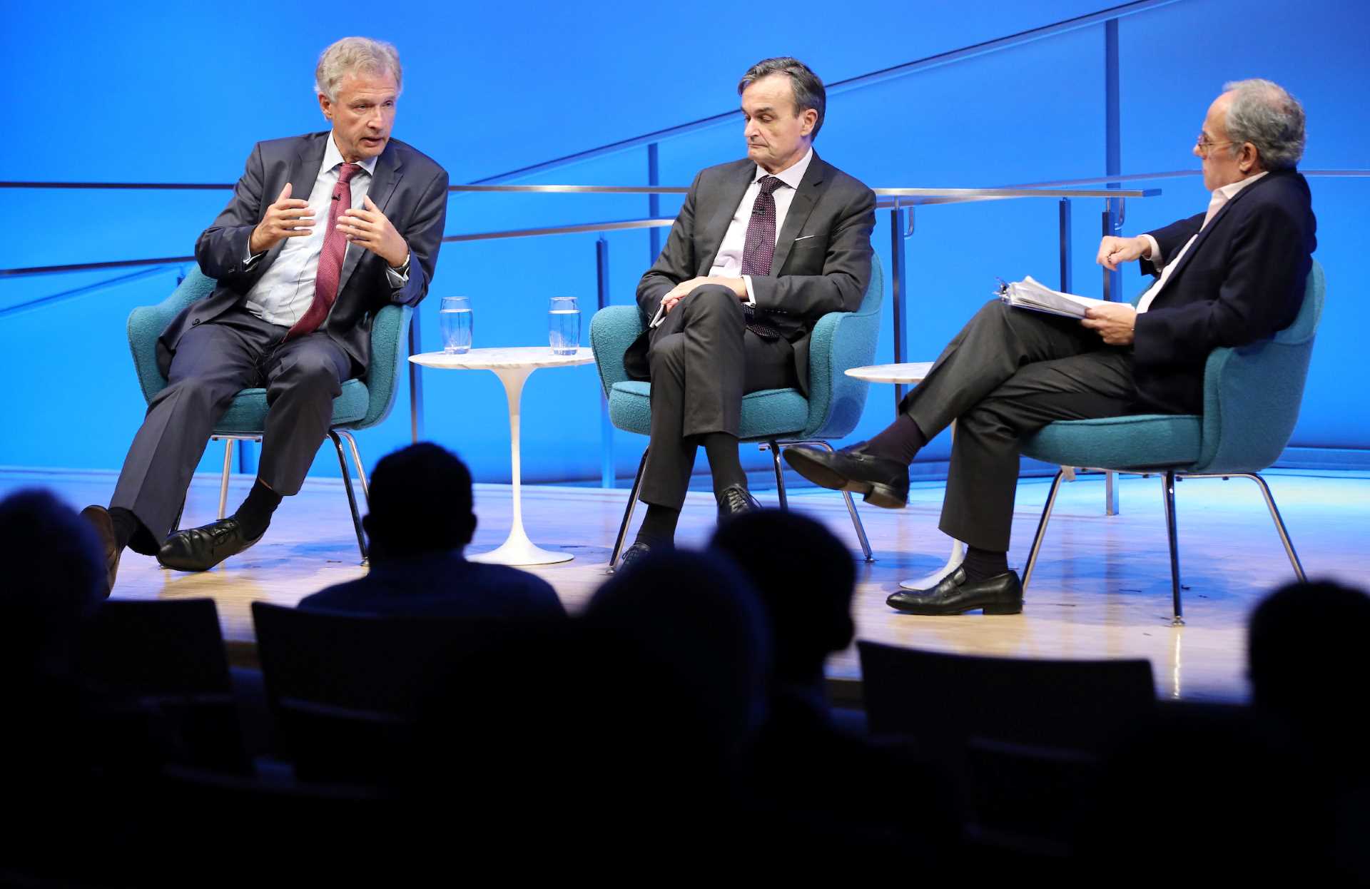 The silhouettes of audience members are visible in the foreground as Peter Ammon, former Ambassador of Germany to the U.S., speaks onstage during a public program in the Museum auditorium. He is seated next to Gérard Araud, former Ambassador of France to the U.S., and Clifford Chanin, the executive vice president and deputy director for museum programs.