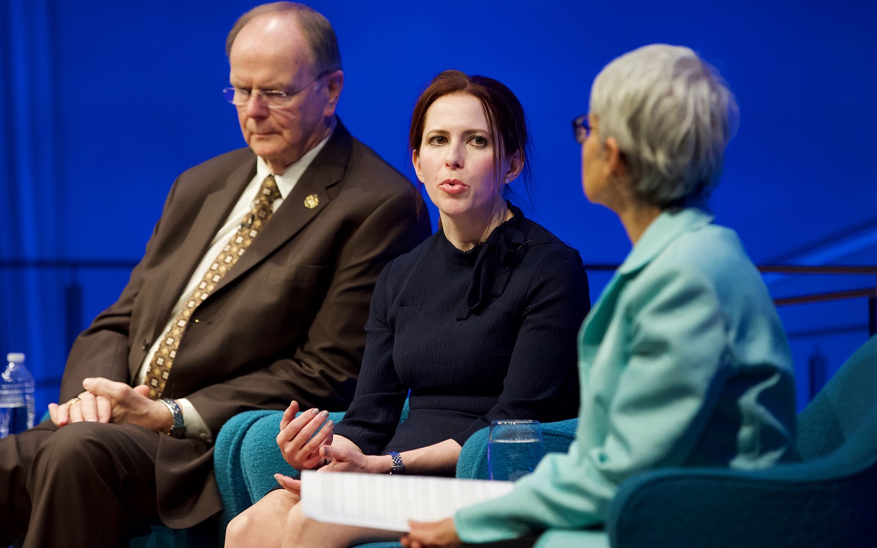 A moderator is seated out of focus in the foreground as she looks towards two guests during a public program at the Museum’s Auditorium. Speaking to her right is artist Melissa Cacciola. To Cassiola’s right is Local 40 Business Manager Robert Walsh. The blue lights from the stage light up the wall behind the three of them.