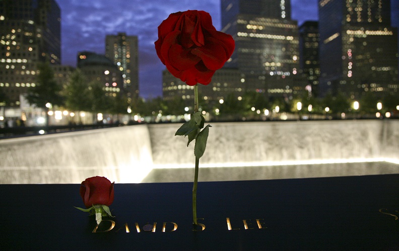 Two red roses left on the 9/11 Memorial parapet at night.