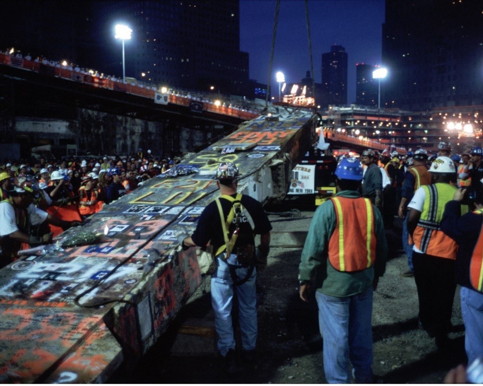 Rescue and recovery workers in vests and hard hats cut down the Last Column, at night in May 2002
