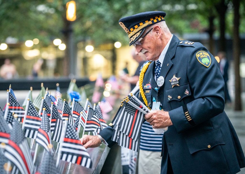 a member of the NYPD places flags on the Memorial