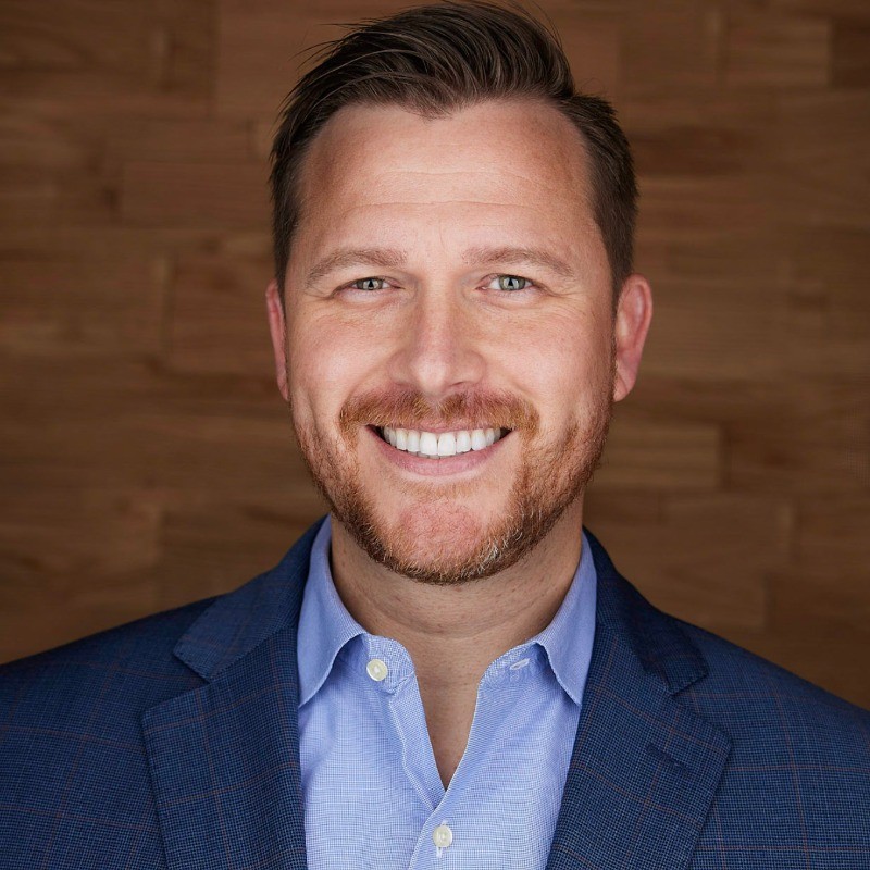 John Paluska, bearded, wearing a light blue shirt and a darker blue blazer