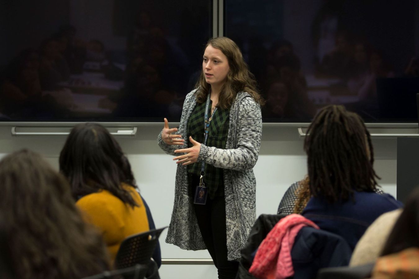 a teacher in a sweater presents to a room