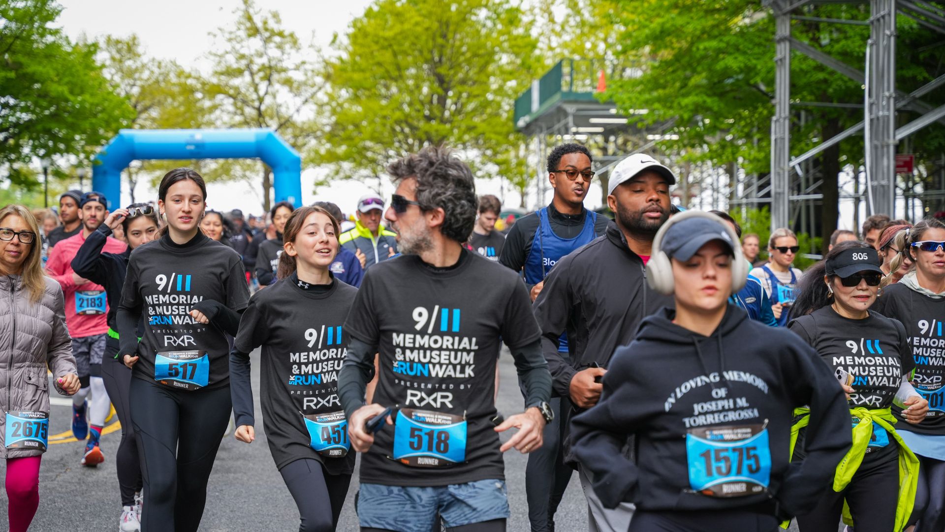 Runners and walkers in navy blue t-shirts just after the start line at the 5K