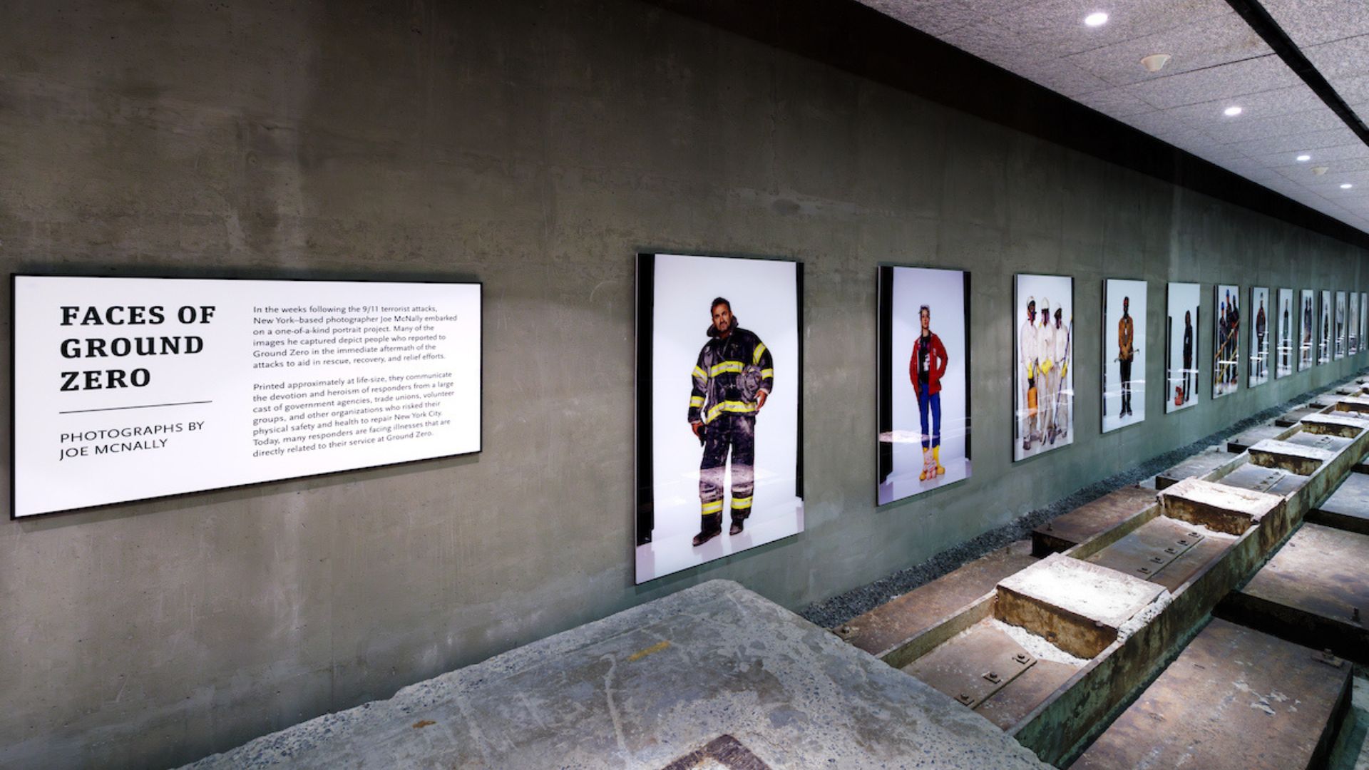 View of a museum gallery that displays large portraits of first-responders. An introductory sits on the left with the text "Faces of Ground Zero."