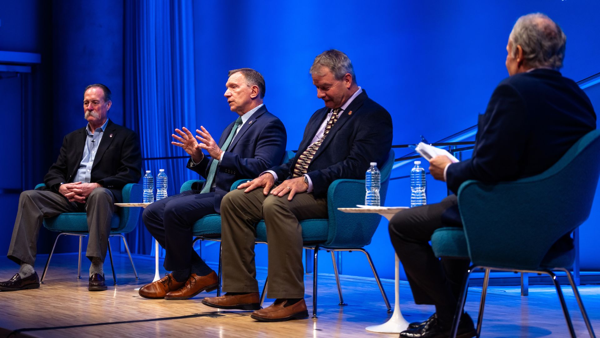 Panelists on stage against a bright blue curtain.