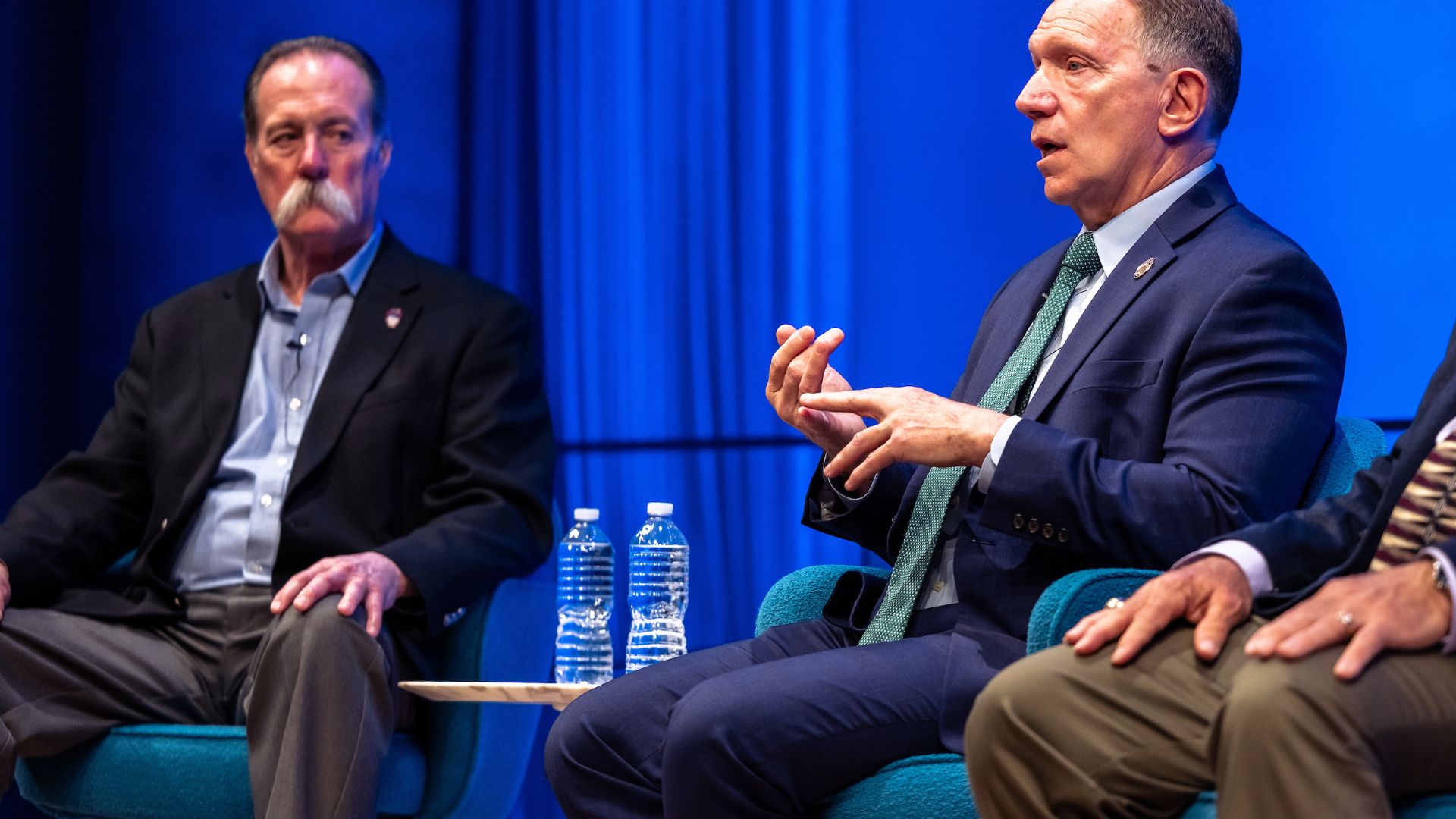 Panelists on stage against a bright blue curtain.
