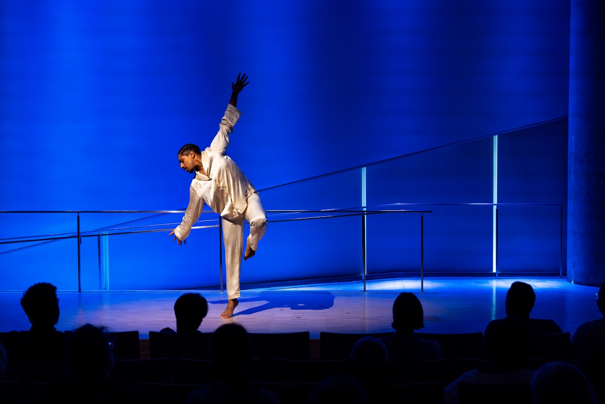 a dancer with arms wide balances on one foot