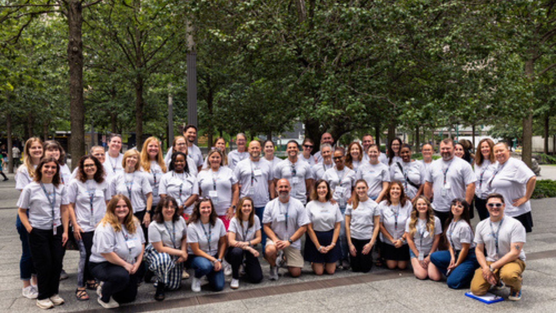 Several rows of people wearing matching white t-shirts poses on the Memorial