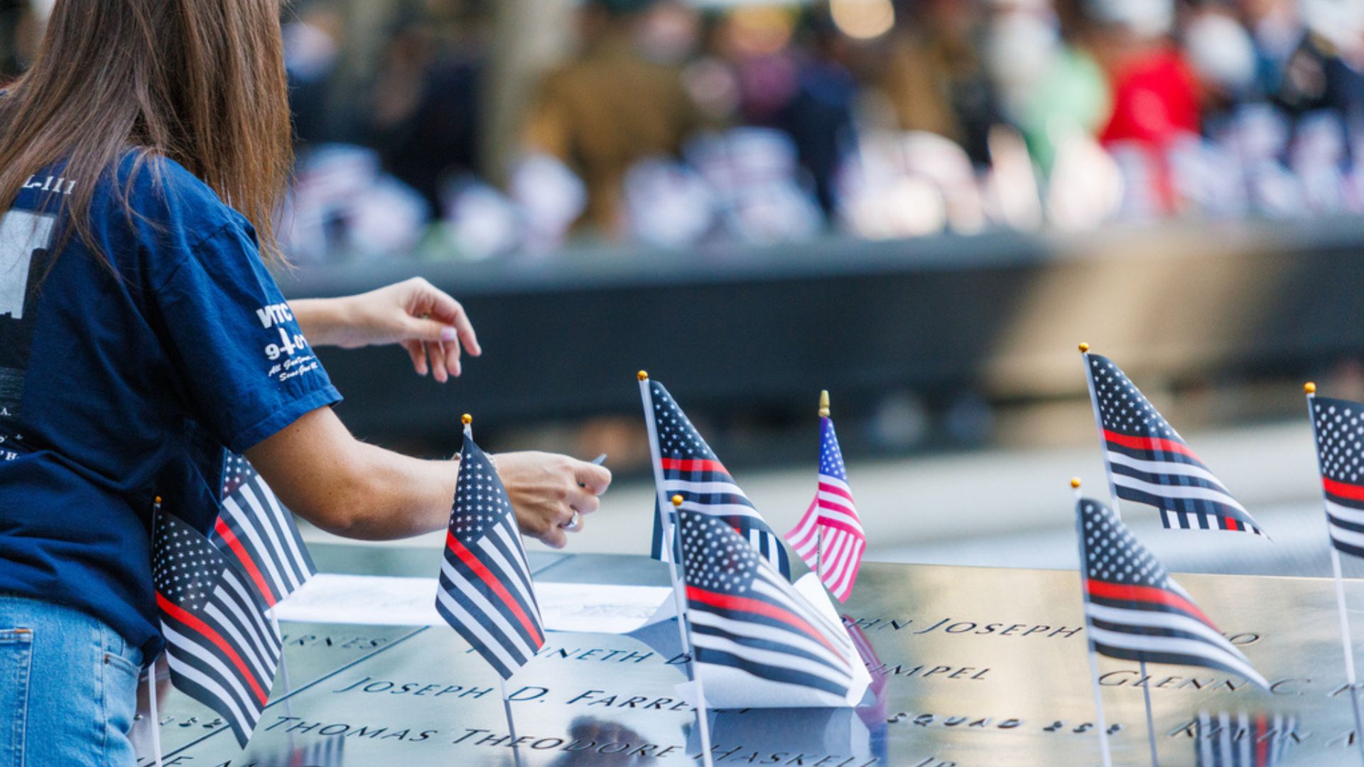 A woman places American flags on the Memorial