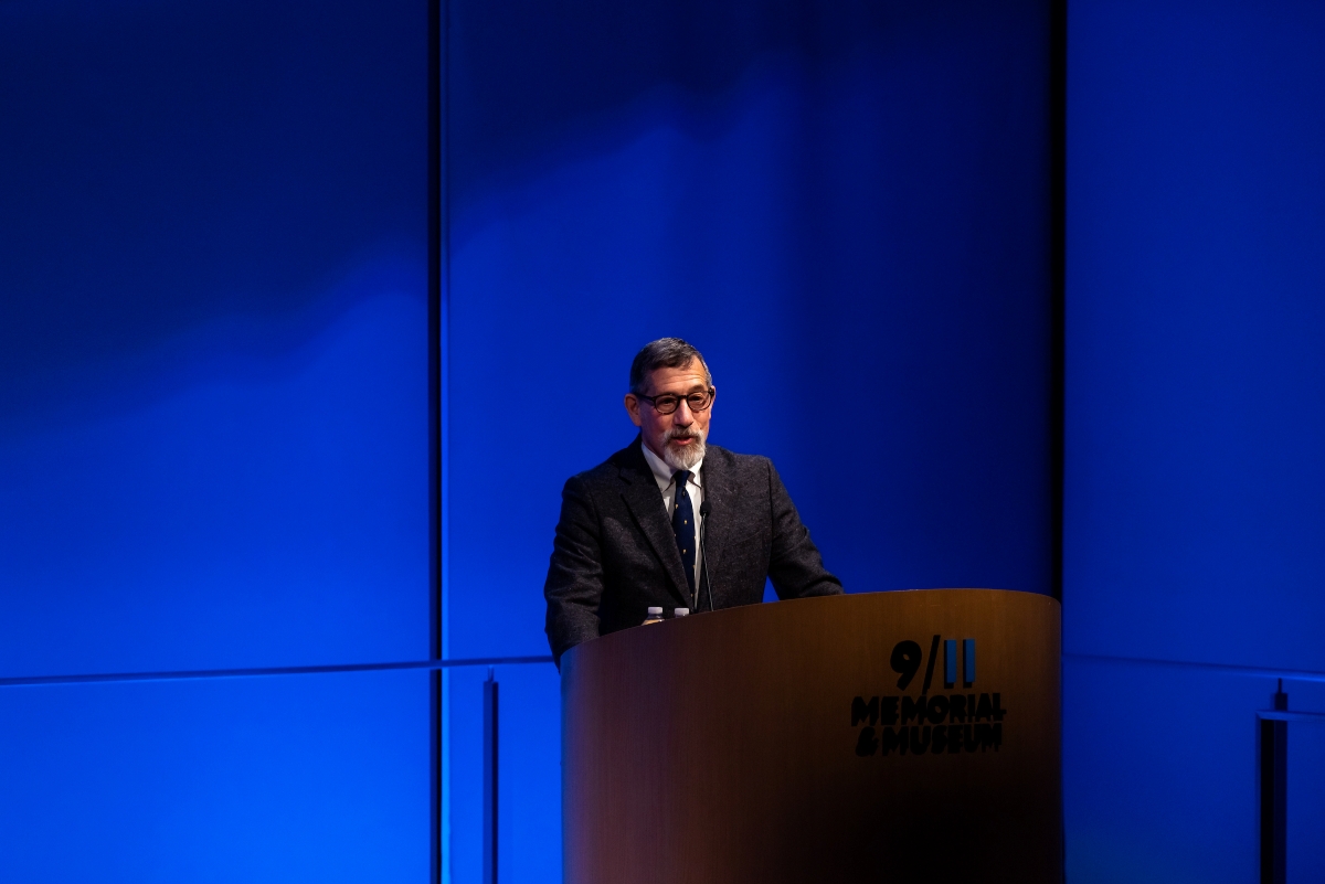 a man stands behind a podium in front of a blue curtain