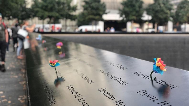 Image of Memorial parapet with multi-colored paper flowers 