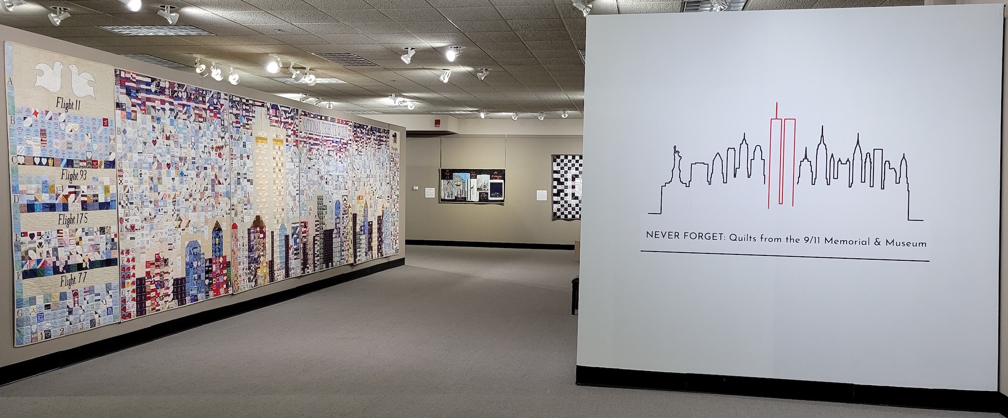 A beige-carpeted gallery space, brightly lit, displays quilts from the Museum's collection 