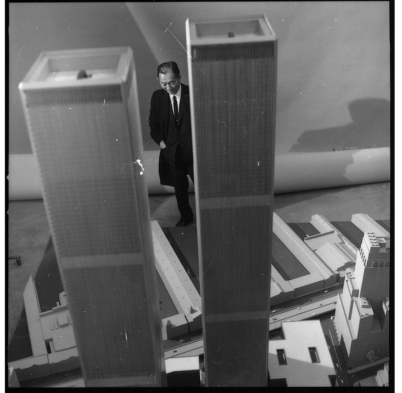 Black-and-white photograph showing aerial view of the Twin Tower model with indiscernible man standing behind, visible between the two towers.