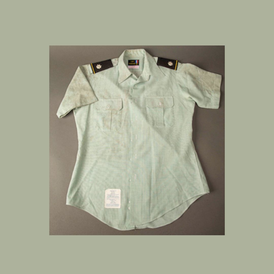Light green short-sleeved military shirt laid out on gray background