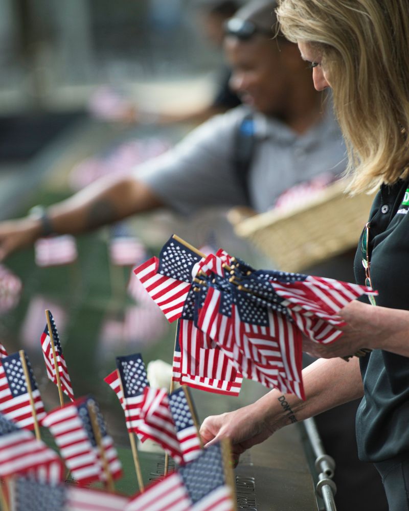 Small American flags are placed in names along the 9/11 Memorial