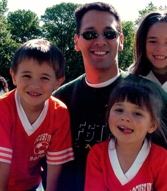 a group including a man and three children smile for the camera