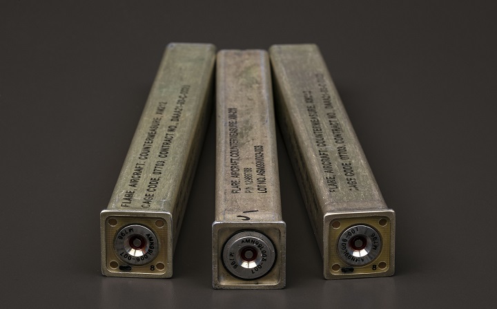 Three metal casings in the shape of square cylinder with indiscernible writing on them.