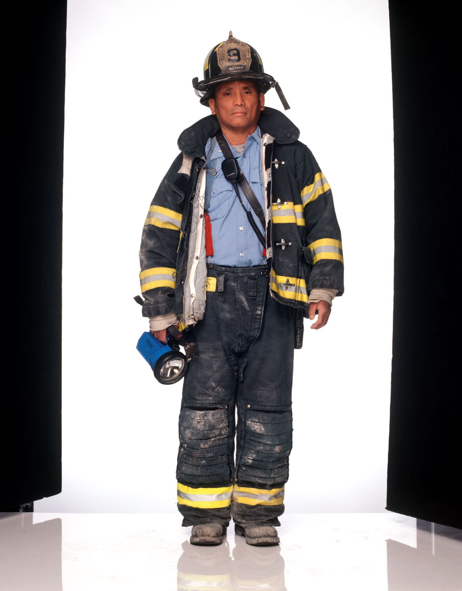 Lieutenant Jacob Chin, FDNY Engine Company 9 standing in his gear between two black columns