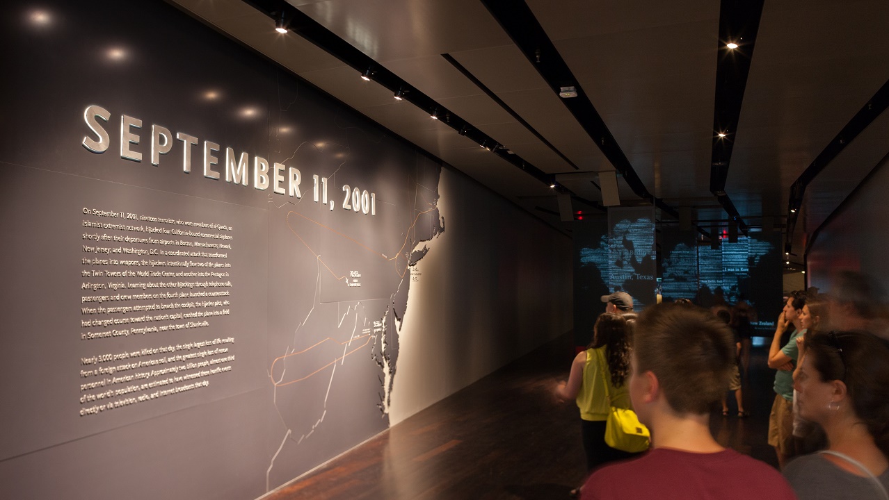 Museum visitors look at a wall of text that begins with the headline September 11, 2001.