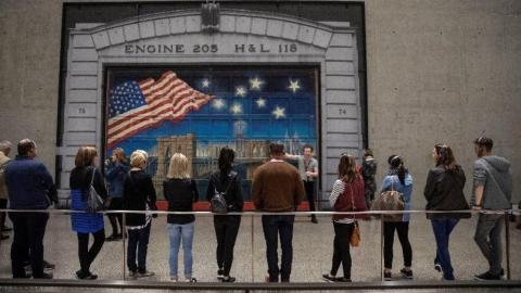 Back view of Museum visitors as they look at a firehouse garage door memorializing fallen firefighters