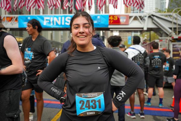 A woman smiles with her hands on hips