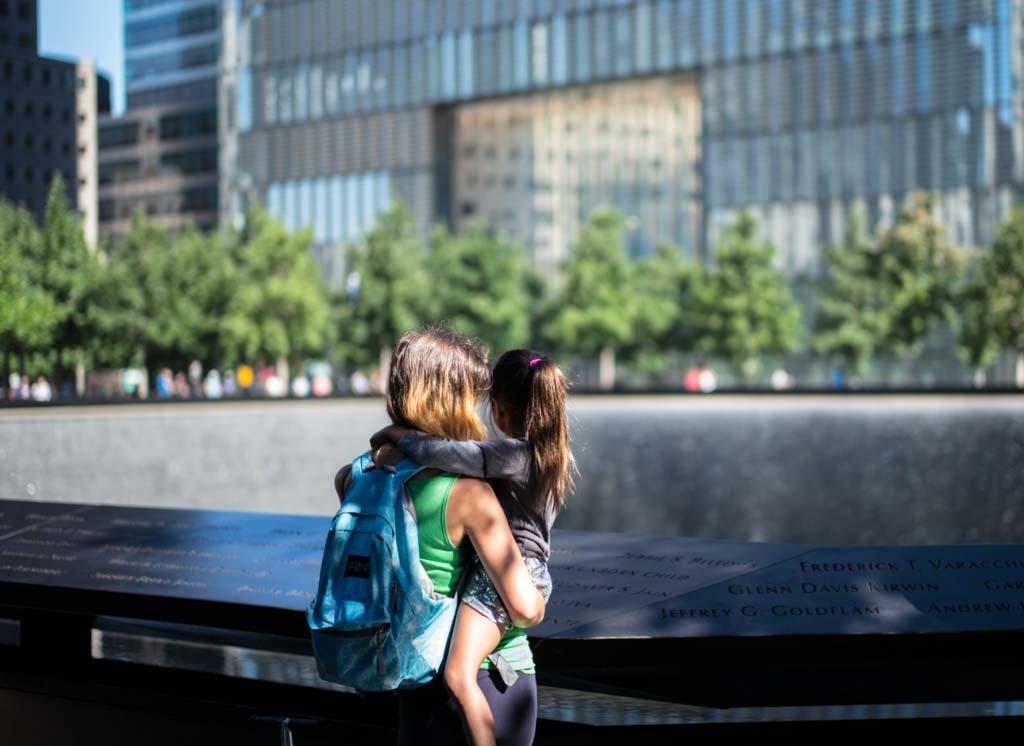 Image of the back of a woman holding a young child looking over the Memorial