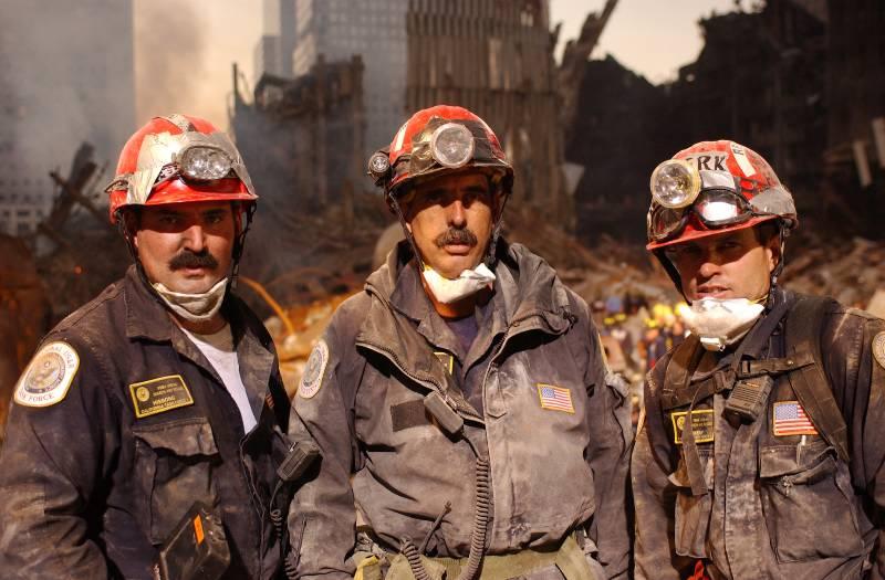 Three men wearing hard hats, covered in dust, at Ground Zero