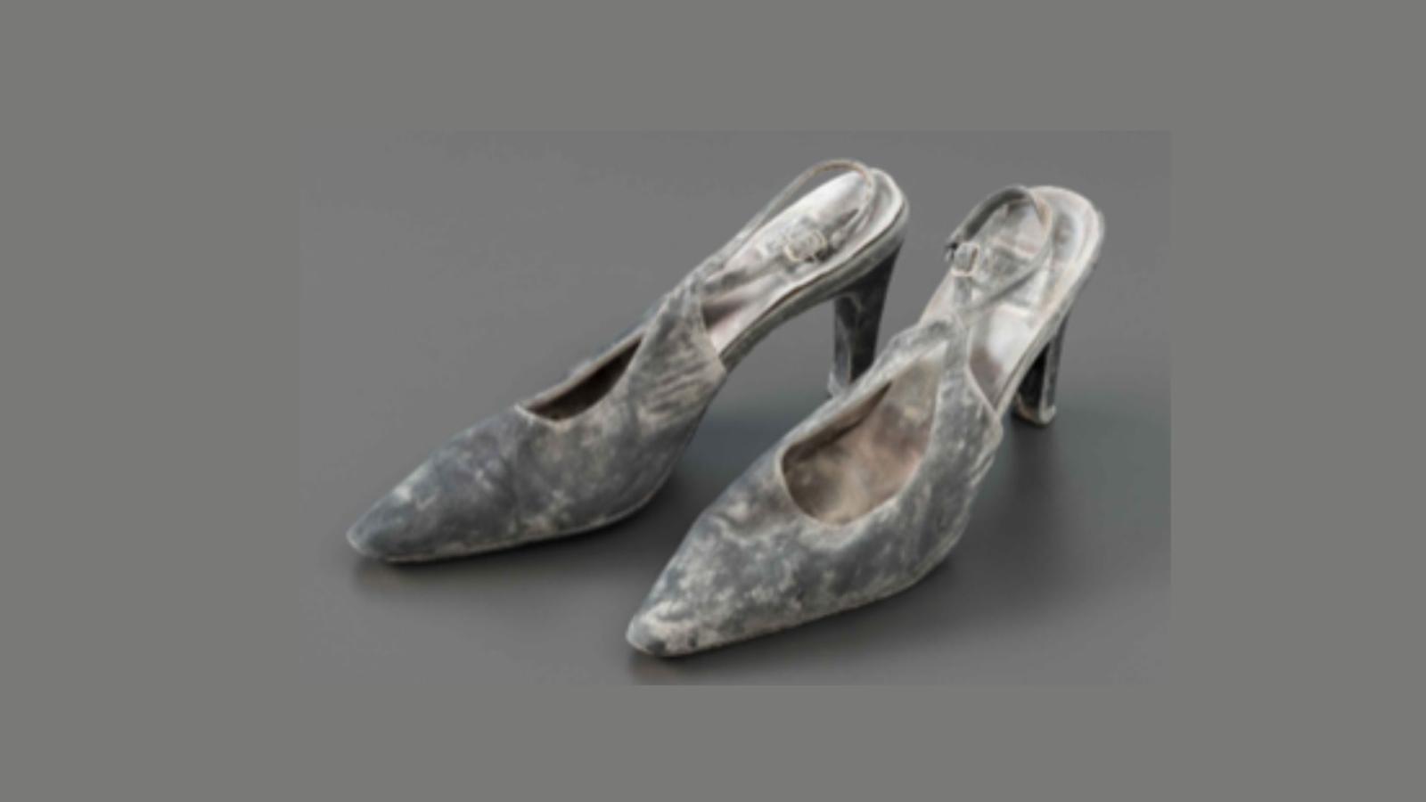 A battered pair of women's shoes, high-heeled and covered in soot
