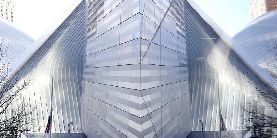 The bright white Oculus transportation hub reflects off a glass facade of the 9/11 Memorial Museum.