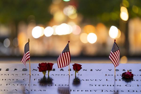 Three, small American flags and several red roses have been placed as tributes at the names of victims on the 9/11 Memorial. 