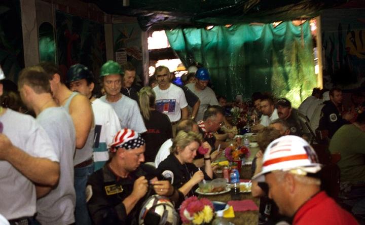 In this archival photo, rescue and recovery workers sit for a meal or line up to get their food in an informal restaurant with a green tarp for a door.