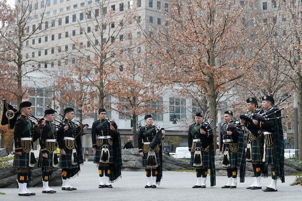 A half circle of kilted bagpipe players on the Memorial 