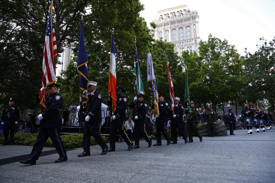 Uniformed officers carry flags in a procession on the plaza
